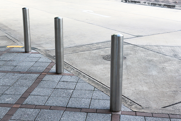 Stainless Steel bollards on grey stone pavement of car park